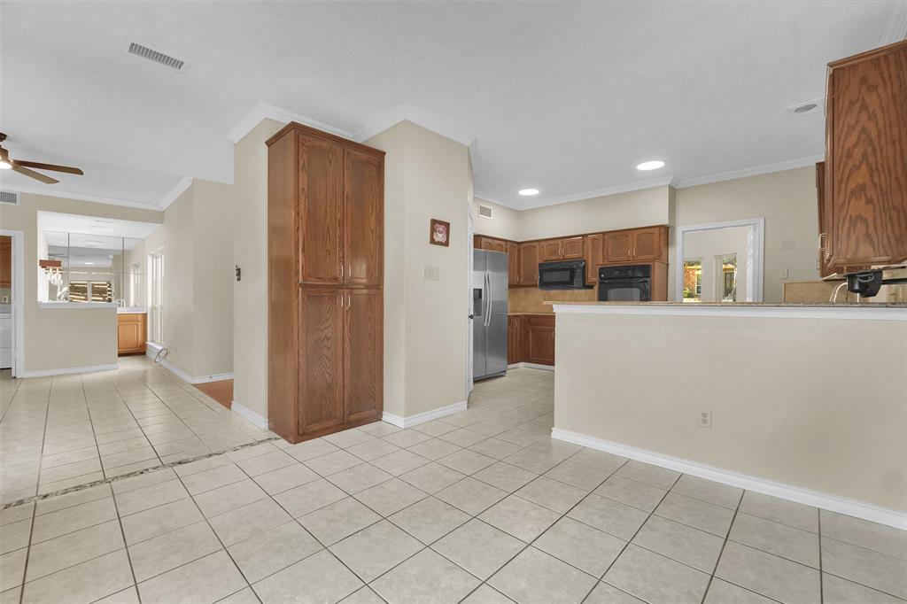 Kitchen featuring wood cabinetry, stainless steel appliances, neutral tile flooring, recessed lighting, and a peninsula countertop