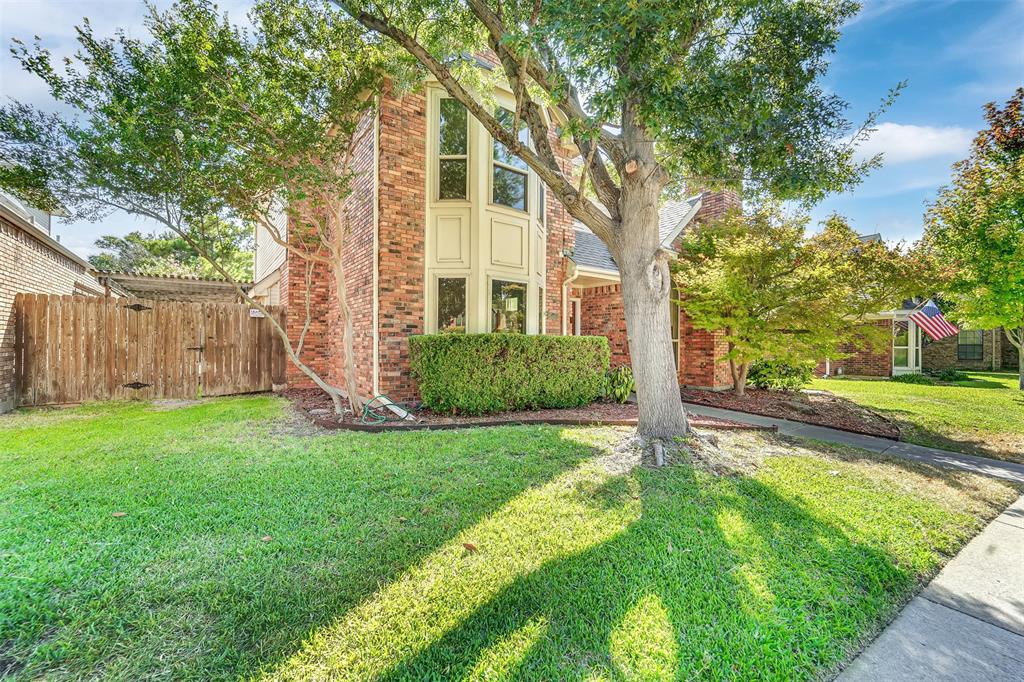 Two-story brick exterior featuring a multi-pane bay window, wood privacy fencing, and mature landscaping