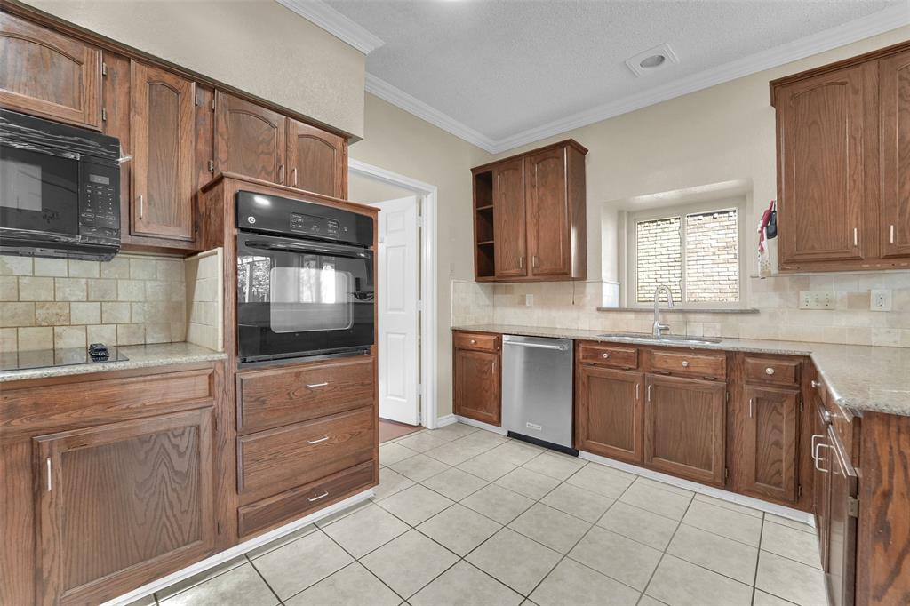 Kitchen featuring wood cabinetry, stone-finish countertops, tile backsplash, built-in wall oven, and stainless steel dishwasher