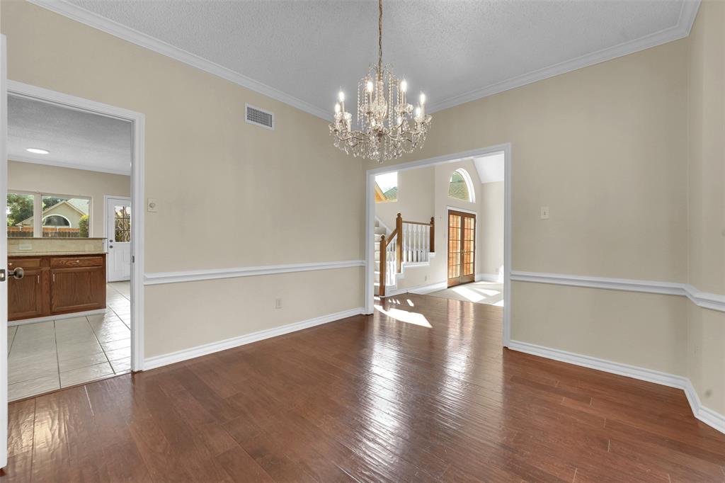 Dining room featuring wood-finish flooring, chair rail molding, and a crystal chandelier