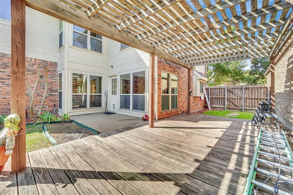 Large wood deck featuring a built-in pergola, brick and siding exterior, and wood privacy fencing