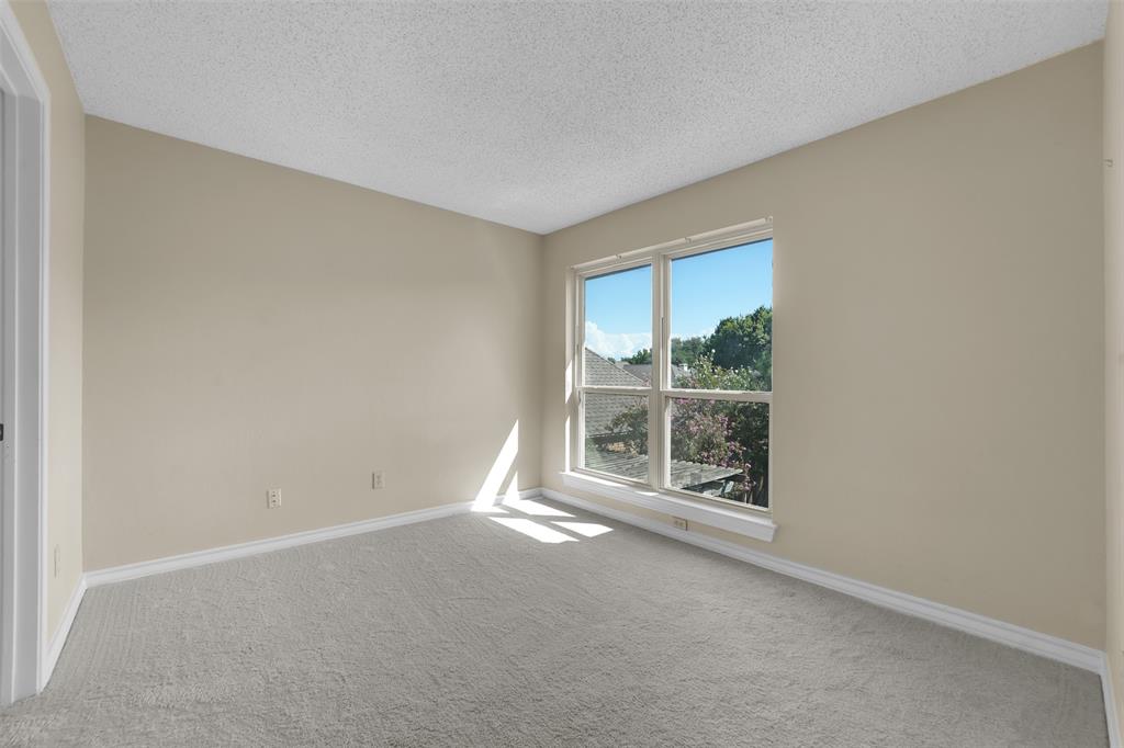 Neutral-toned interior space featuring textured ceiling, neutral wall paint, and wall-to-wall carpeting