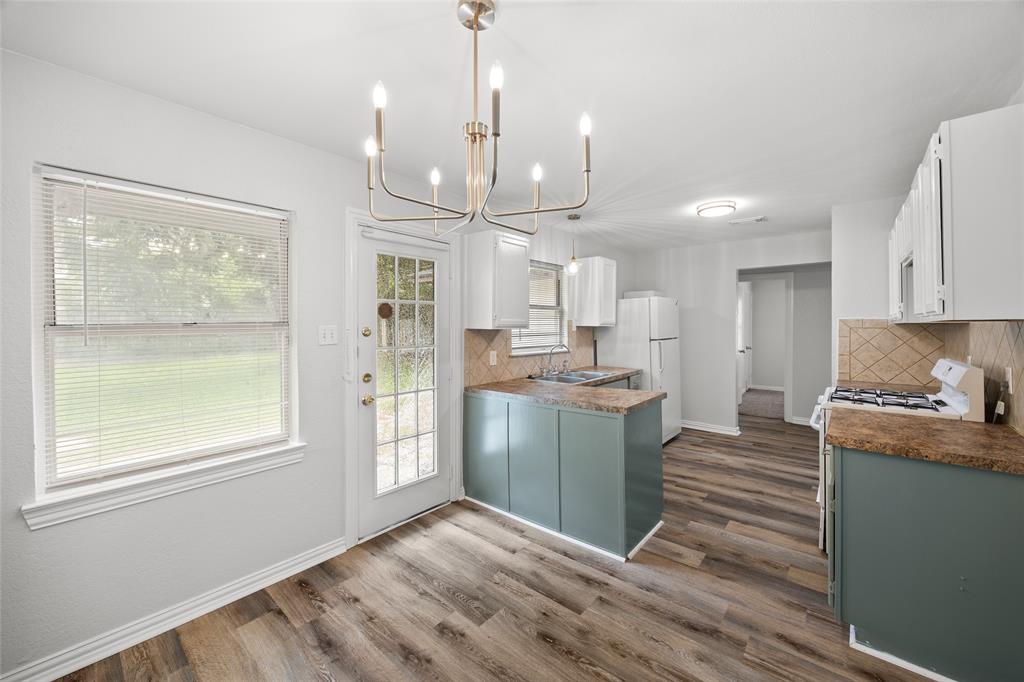 Eat-in kitchen featuring wood-finish flooring, white walls, and a multi-light chandelier