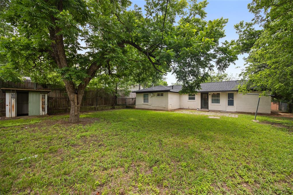 Spacious backyard featuring a large mature tree, green lawn space, and a wood privacy fence