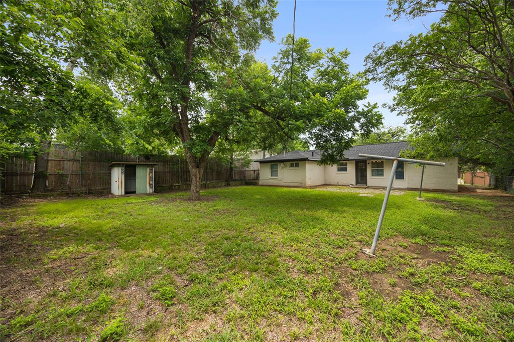 Spacious backyard featuring established trees, a storage shed, and a privacy fence