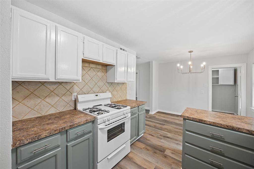 Kitchen featuring two-tone cabinetry with white upper cabinets and gray lower cabinets, a gas range, diamond-patterned tile backsplash, and wood-finish flooring