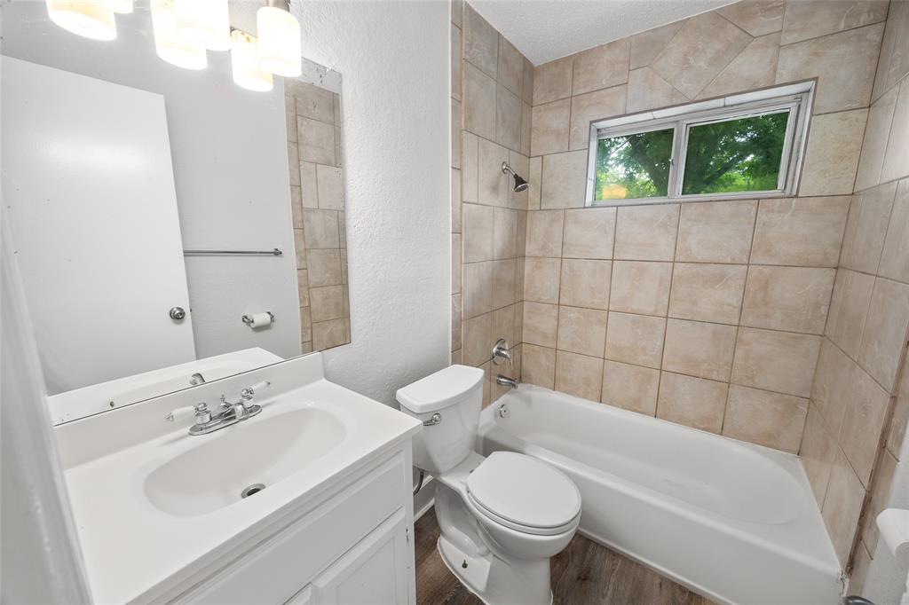 Bathroom featuring a white vanity with integrated sink, chrome faucet, and a large wall mirror