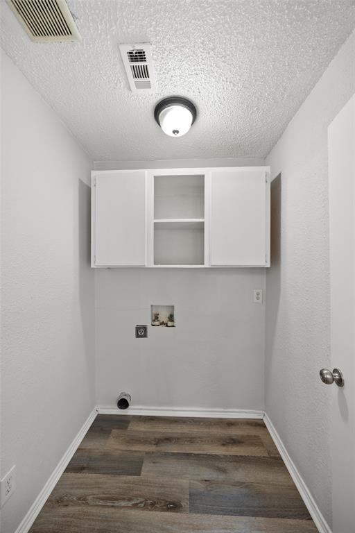 Dedicated utility space featuring overhead cabinetry and wood-finish flooring