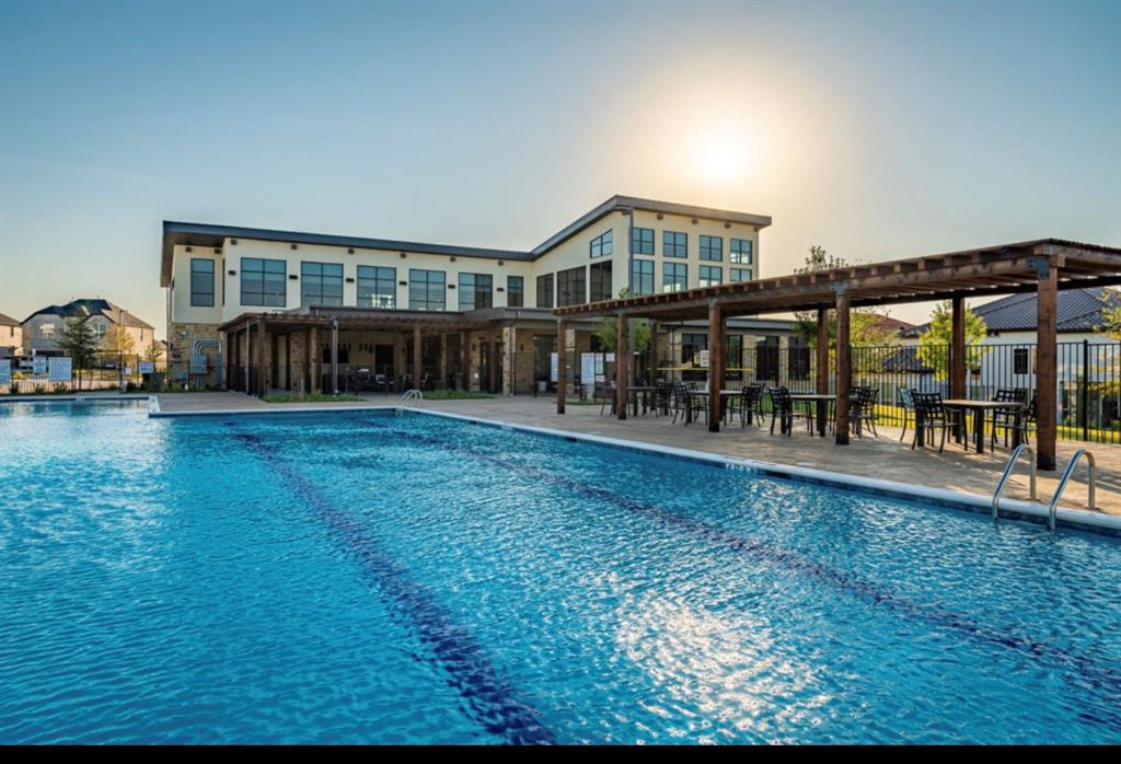 Community pool featuring a multi-lane lap design, stone-paved decking, and a timber-framed pergola structure