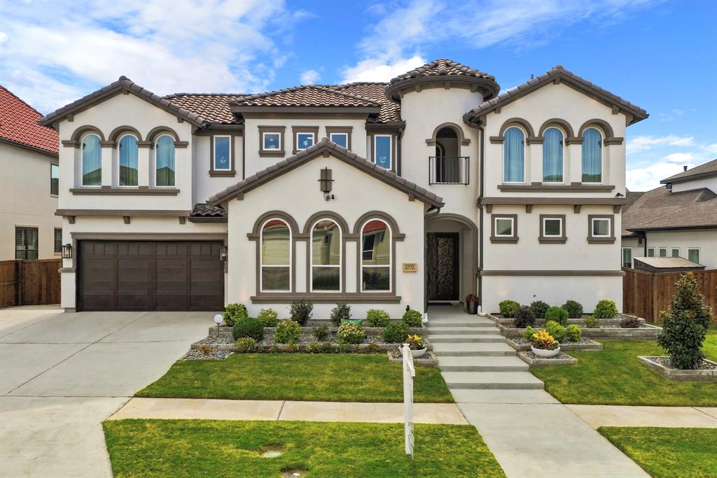 Stucco exterior featuring arched windows, a multi-gabled tile roof, decorative turret, and attached multi-car garage