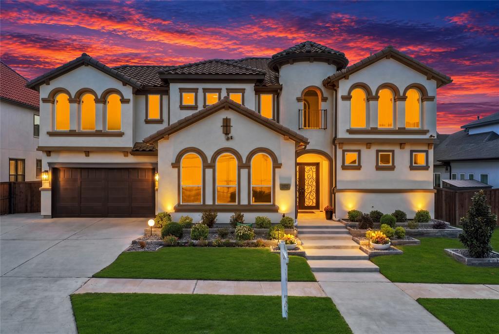 Stucco exterior featuring arched windows, tile roofing, a turret architectural detail, decorative metal front door insert, and an attached multi-car garage