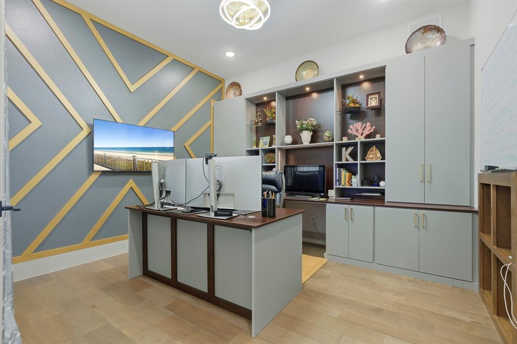 Custom wall detailing featuring geometric gold-tone trim, built-in floor-to-ceiling cabinetry with integrated display shelving, recessed lighting, and wood-finish flooring