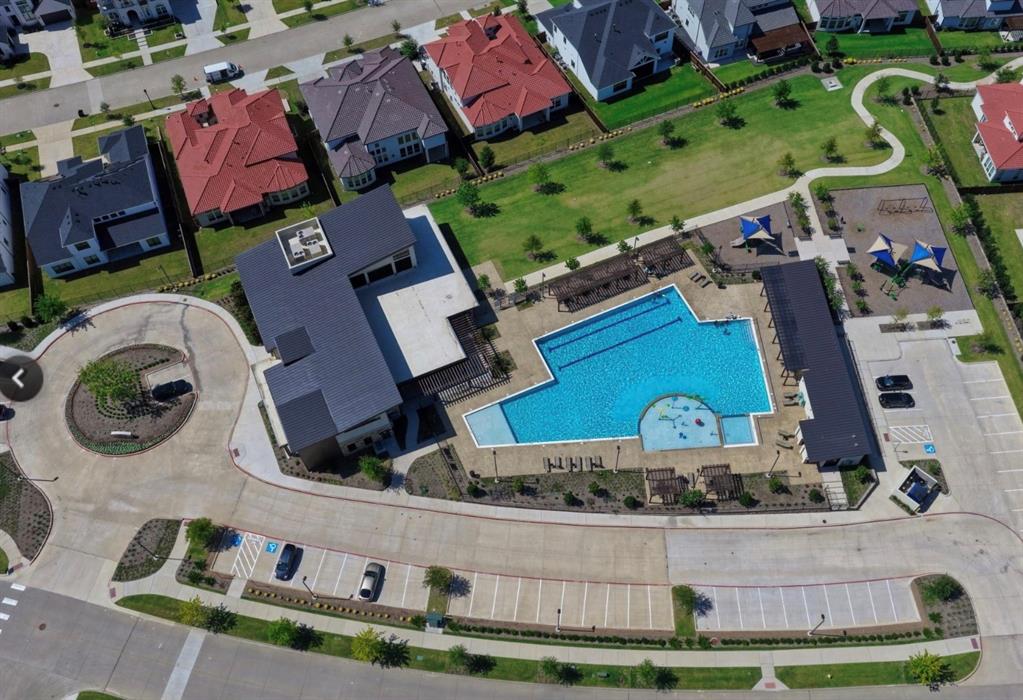 Community recreation center featuring a swimming pool, lap lanes, playground structures, paved parking areas, and manicured green space