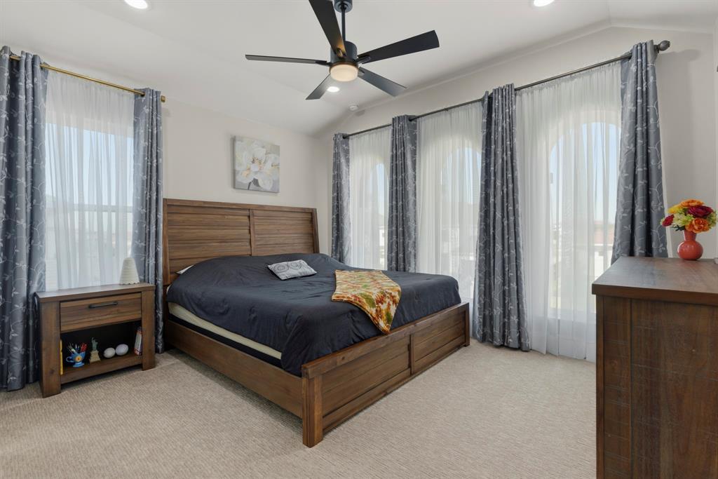 Vaulted ceilings, three arched windows, wall-to-wall carpeting, and a matte black ceiling fan