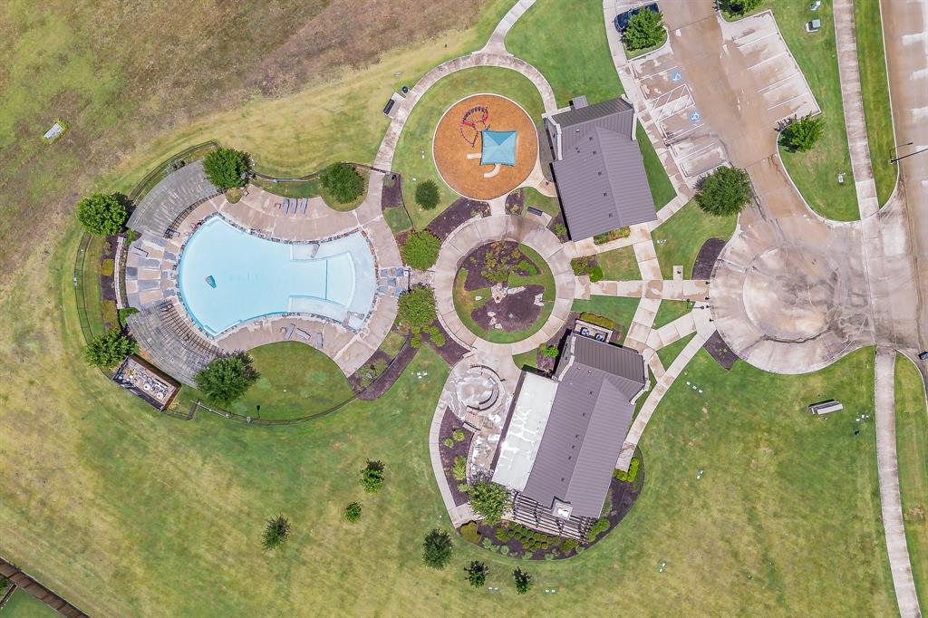 Community recreation area featuring a large swimming pool, playground, two amenity buildings, and paved pathways