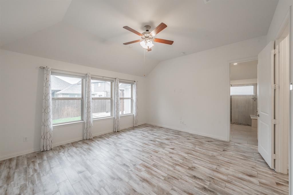 Unfurnished room featuring lofted ceiling, a ceiling fan, light wood-style floors, and baseboards