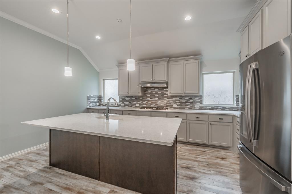 Kitchen featuring stainless steel appliances, a sink, ornamental molding, under cabinet range hood, and decorative backsplash