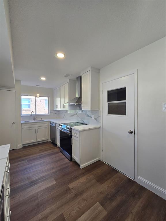 Kitchen featuring white shaker-style cabinetry, stone-patterned backsplash, stainless steel range hood, recessed lighting, and wood-finish flooring