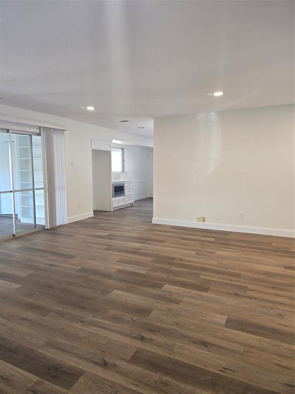 Open floor plan featuring wood-finish flooring, recessed lighting, sliding glass doors, and built-in shelving