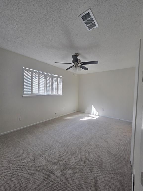 Interior room featuring wall-to-wall carpeting, neutral wall coloring, a multi-blade ceiling fan with integrated lighting, and plantation-style window shutters