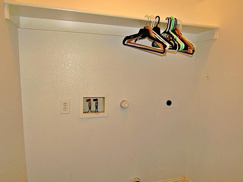 Laundry area featuring built-in shelving, dedicated water supply lines, electrical outlets, and a dryer vent