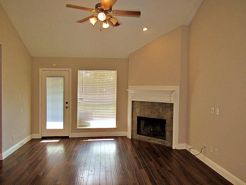 Vaulted ceilings, wood-finish flooring, corner fireplace with tile surround, and built-in mantle