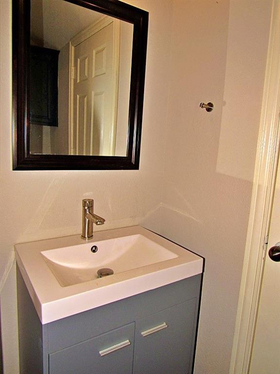 Grey vanity featuring a rectangular integrated sink, brushed metal single-handle faucet, and dark-finish framed wall mirror