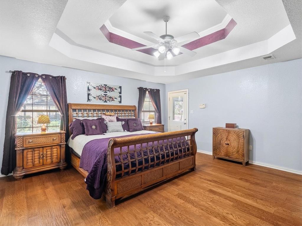 Primary bedroom with wood floors and door to patio pool area