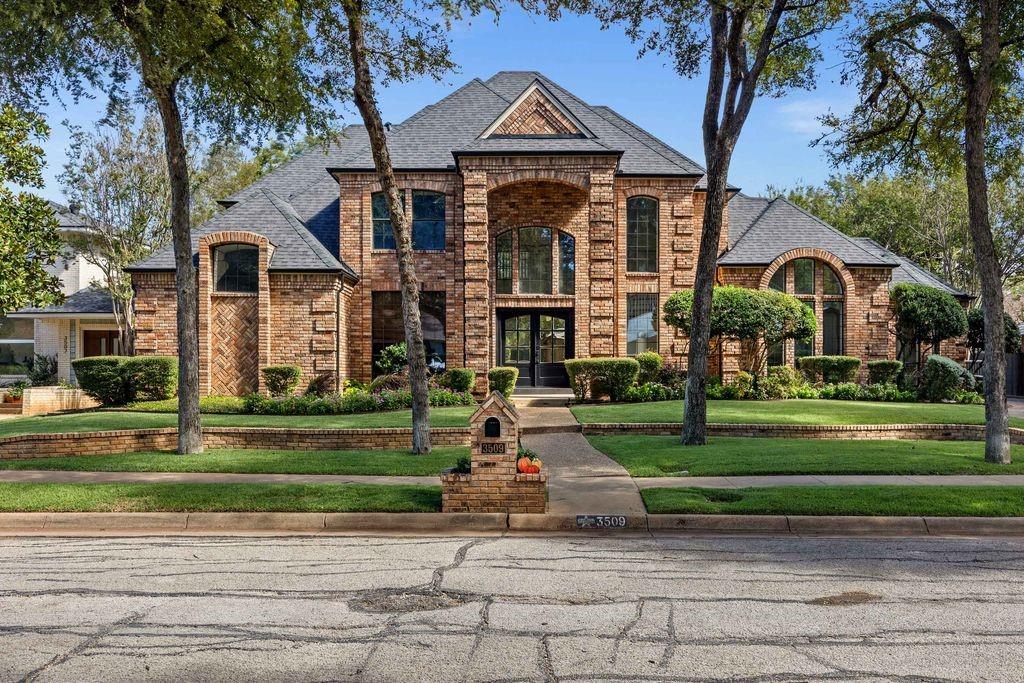 Multi-level brick exterior featuring an arched entryway, decorative masonry detailing, high-pitched roof lines, and a matching brick mailbox