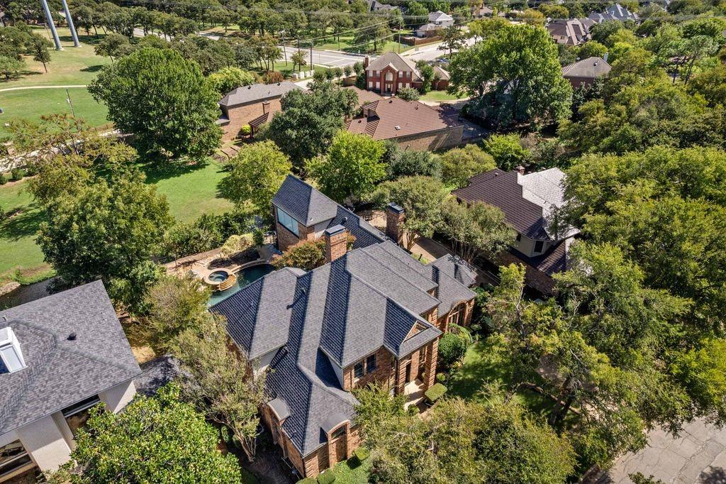 Aerial perspective of a multi-gabled brick residence featuring a multi-level shingle roof, integrated swimming pool with spa, and mature landscaping