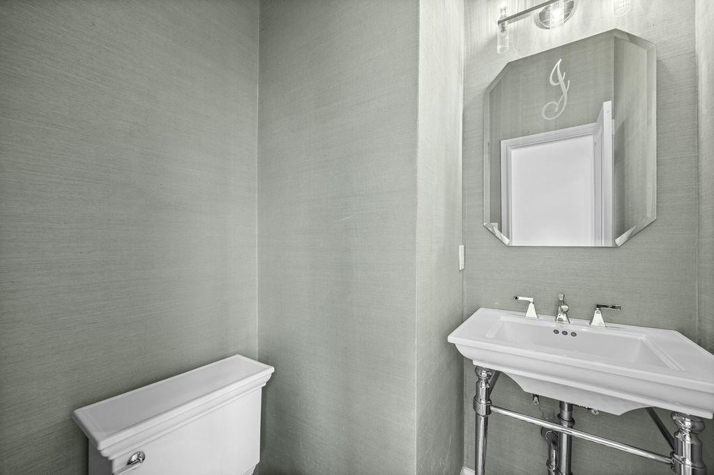 Textured wall coverings, chrome-finished console sink with integrated basin, polished chrome widespread faucet, and beveled-edge wall mirror
