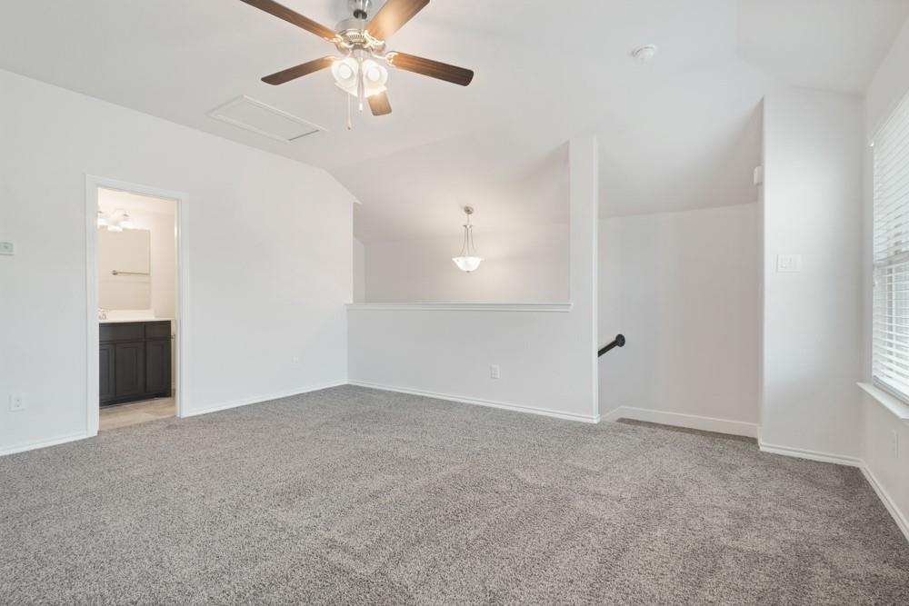Vaulted ceilings, neutral carpeting, ceiling fan with light kit, and multi-pane window