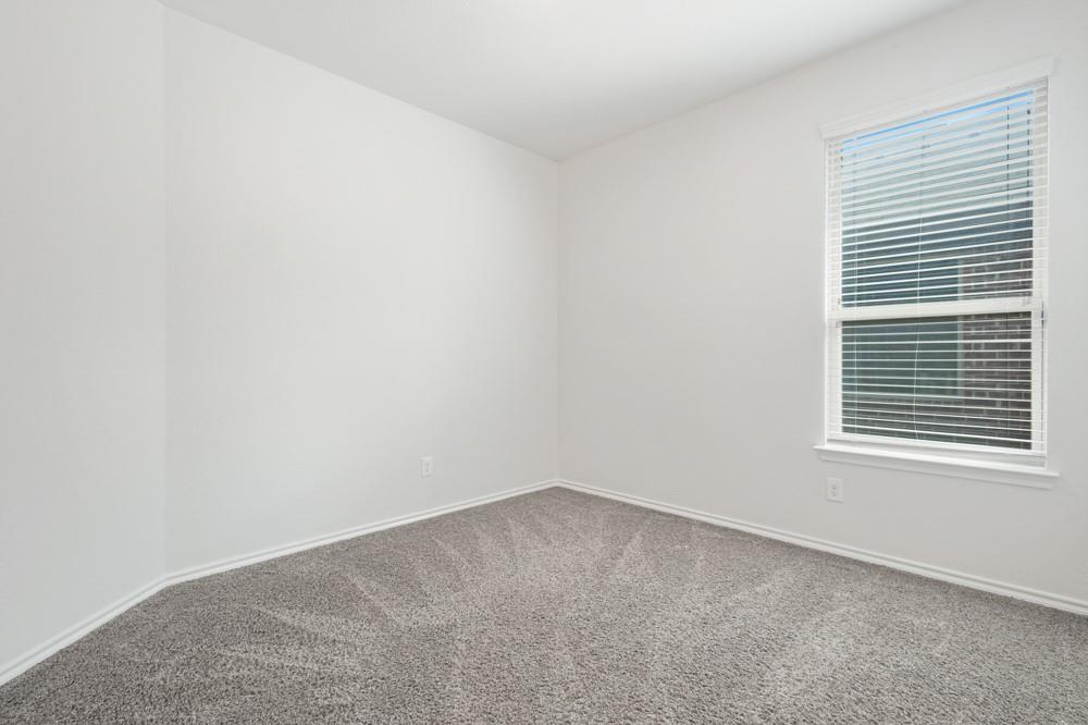 Neutral-toned interior space featuring light-colored wall paint, wall-to-wall carpeting, and a window equipped with horizontal blinds