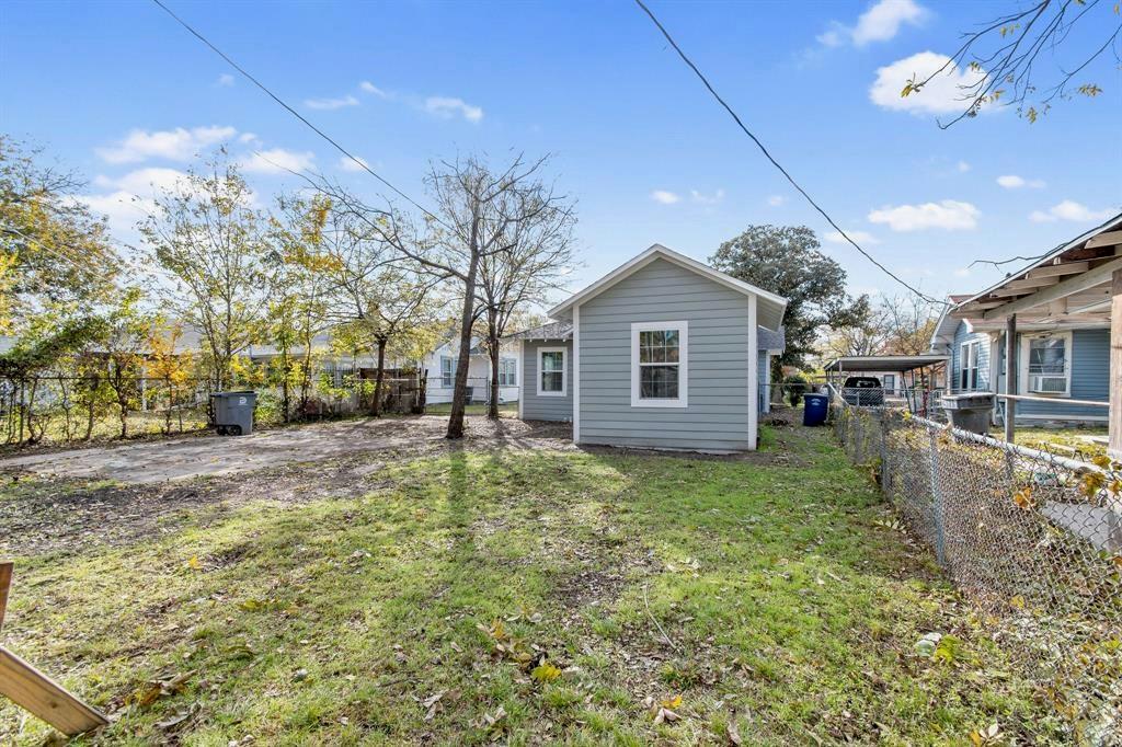 Exterior features include horizontal lap siding, a metal chain-link perimeter fence, and mature trees situated on a level lot