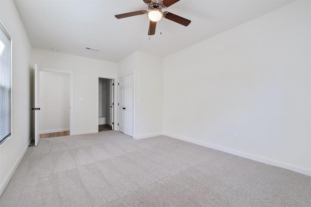 Neutral-toned wall-to-wall carpeting, ceiling fan with integrated lighting, dual-panel interior doors, and window blinds