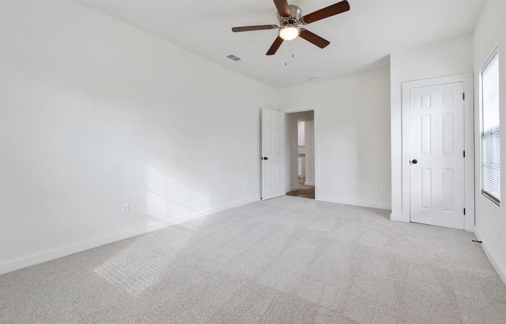 Neutral-toned wall-to-wall carpeting, multi-panel interior doors, and a ceiling-mounted fan with integrated lighting