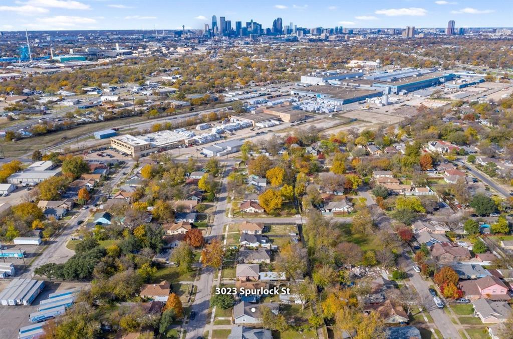 Aerial perspective of 3023 Spurlock St featuring a residential neighborhood setting with prominent city skyline backdrops and mature trees
