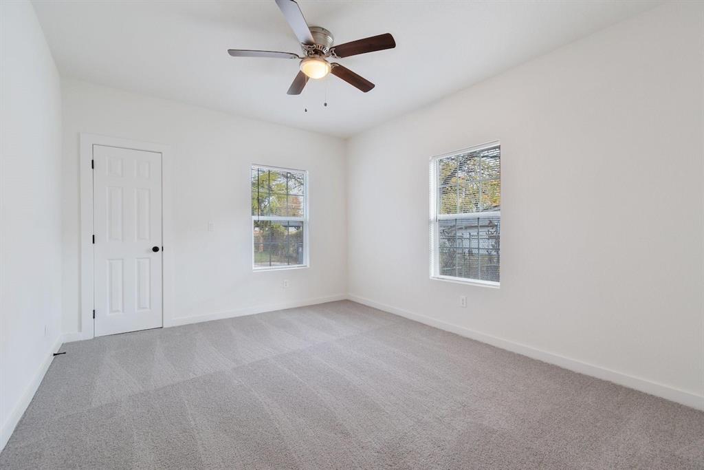 Neutral-toned wall-to-wall carpeting, dual windows, a ceiling fan with integrated lighting, and a solid-core interior door