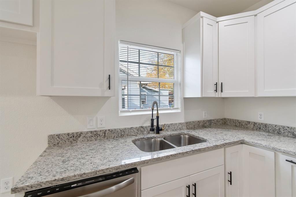 Kitchen featuring white shaker-style cabinetry, speckled stone countertops, dual-basin stainless steel sink, matte black gooseneck faucet, and stainless steel dishwasher