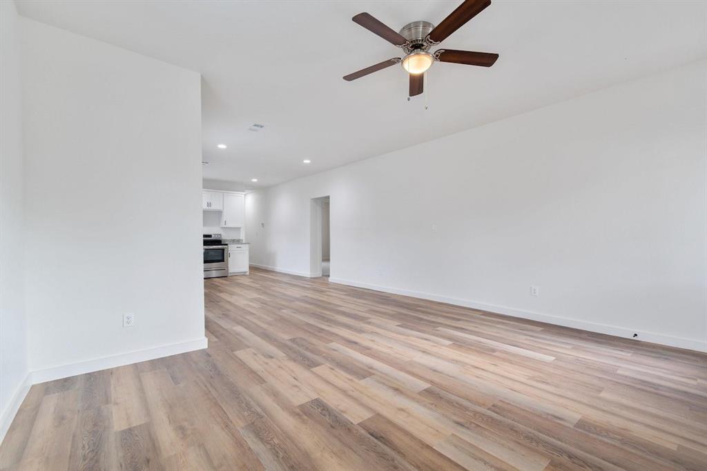 Neutral-toned wall finish, wood-finish flooring, recessed lighting, and a multi-blade ceiling fan with an integrated light fixture