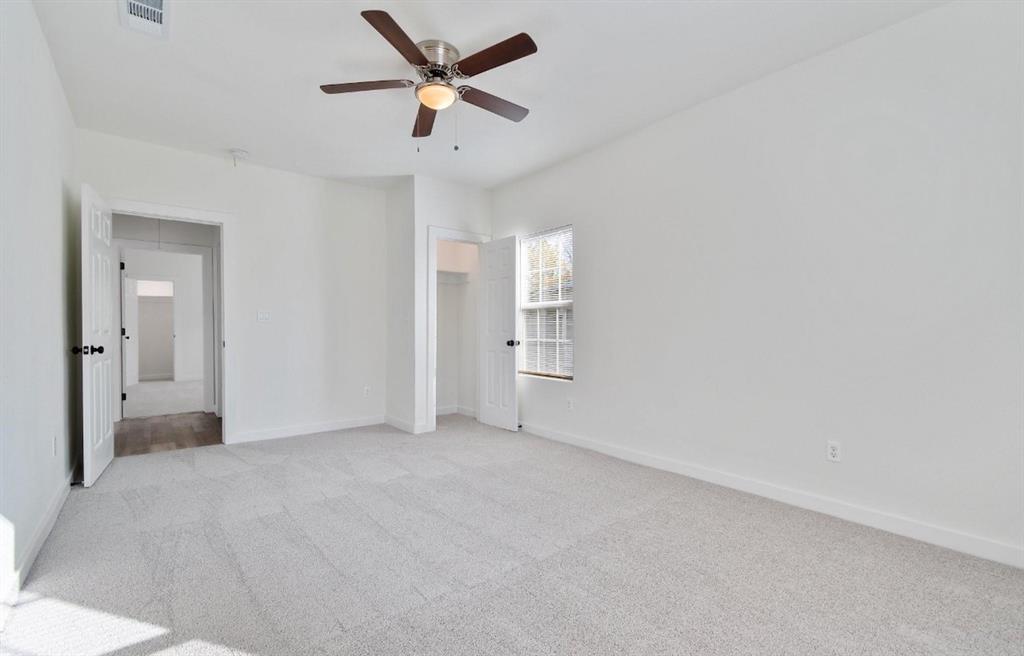 Neutral-toned carpeting, ceiling fan with integrated light fixture, and interior doors