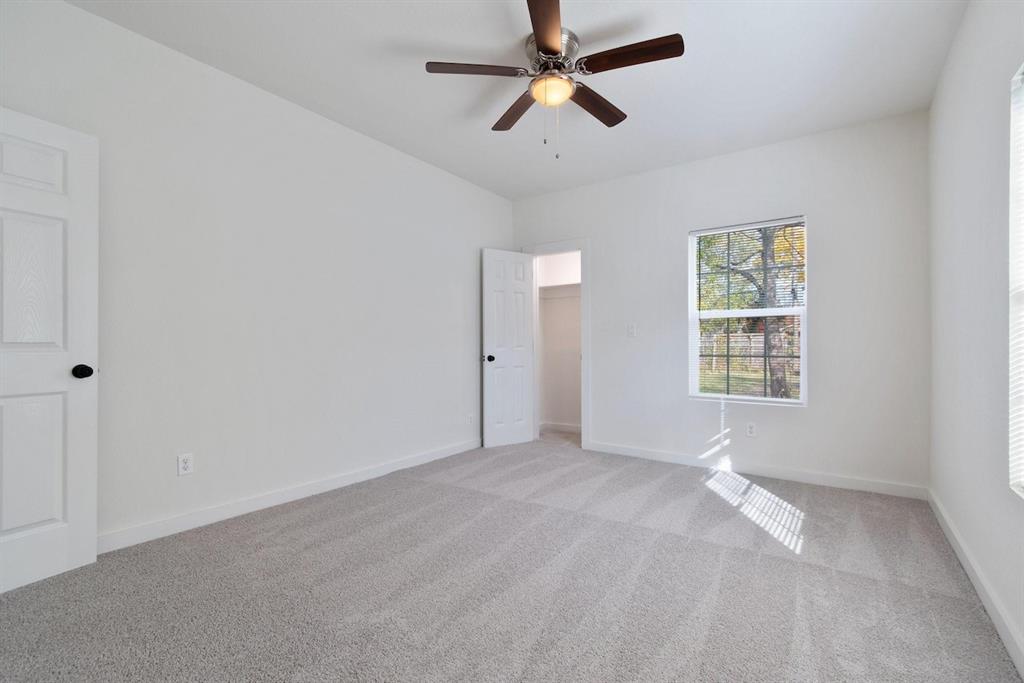 Neutral-toned carpeting, ceiling fan with integrated light fixture, multi-pane window, and interior paneled doors