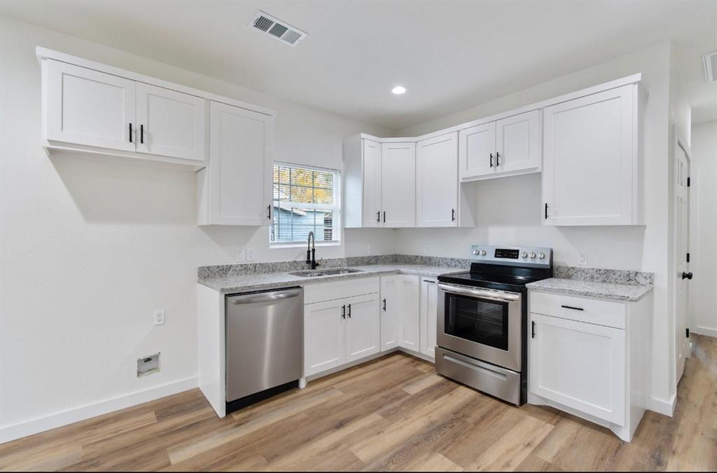 Kitchen featuring white shaker-style cabinetry, stone-finish countertops, stainless steel appliances, a high-arc faucet, and wood-finish flooring