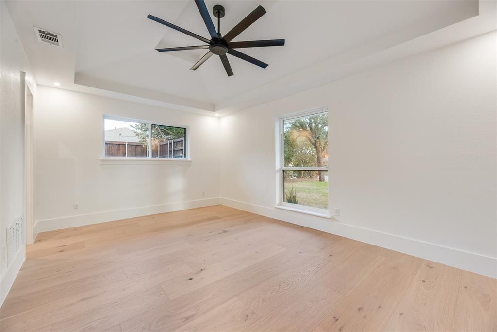 Tray ceiling featuring a multi-blade matte black ceiling fan, wood-finish flooring, and expansive windows