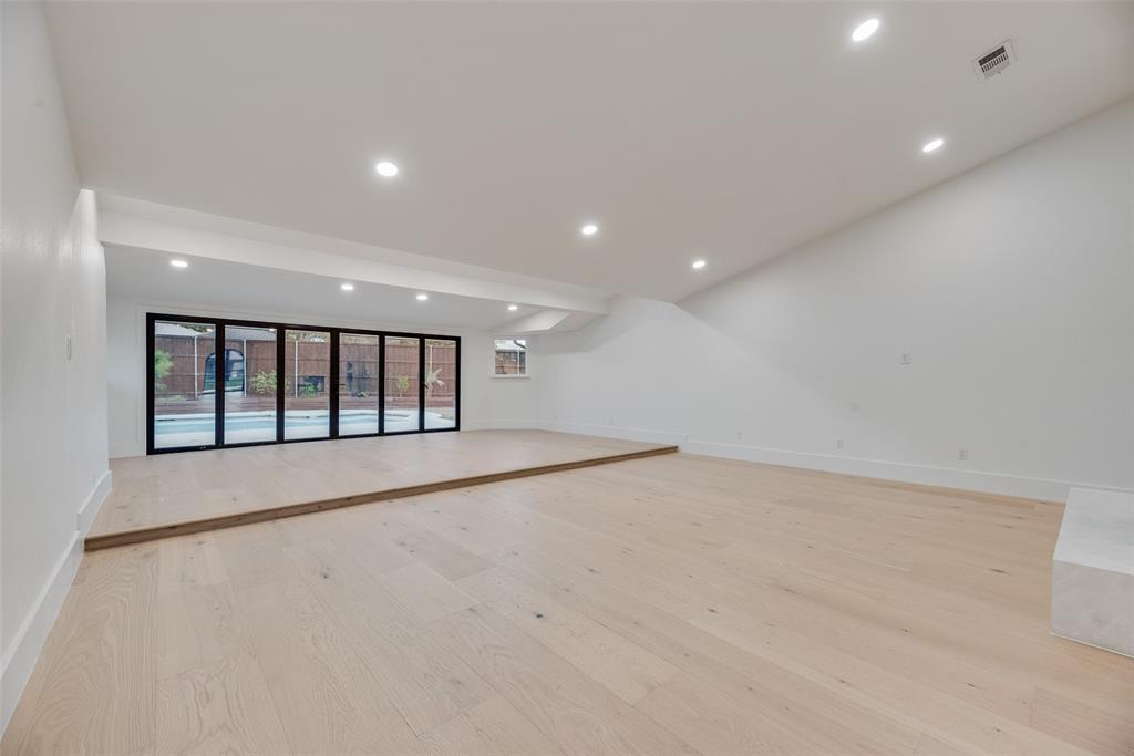 Sunken living area featuring wood-finish flooring, vaulted ceilings, recessed lighting, and multi-panel folding glass doors