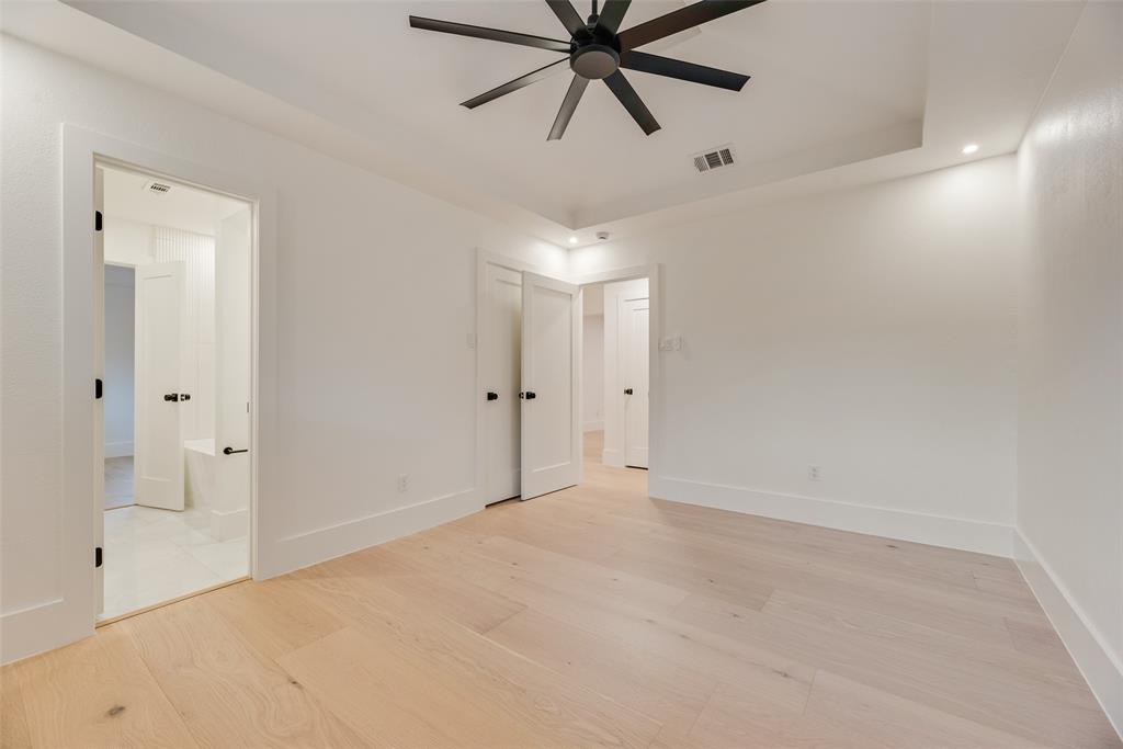 Room featuring wood-finish flooring, tray ceiling, recessed lighting, and a matte black ceiling fan