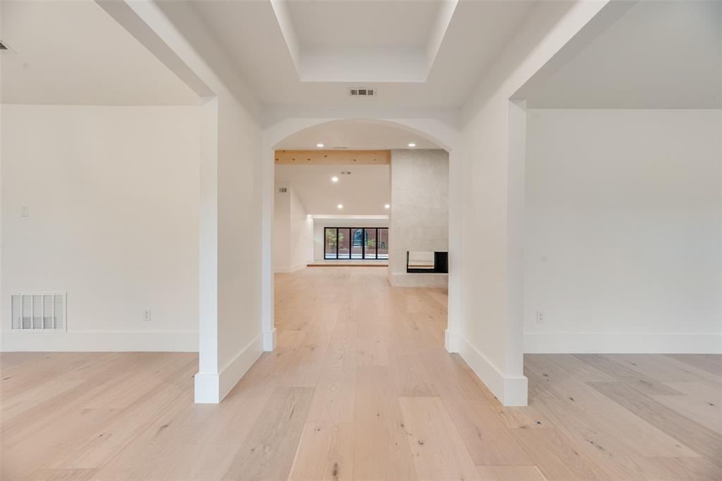 Tray ceiling, arched entryway, wood-finish flooring, recessed lighting, and built-in fireplace