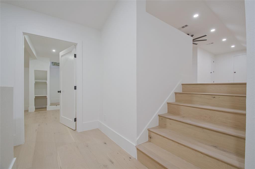 Staircase featuring wood-finish treads, recessed ceiling lighting, and solid-core doors with matte black hardware