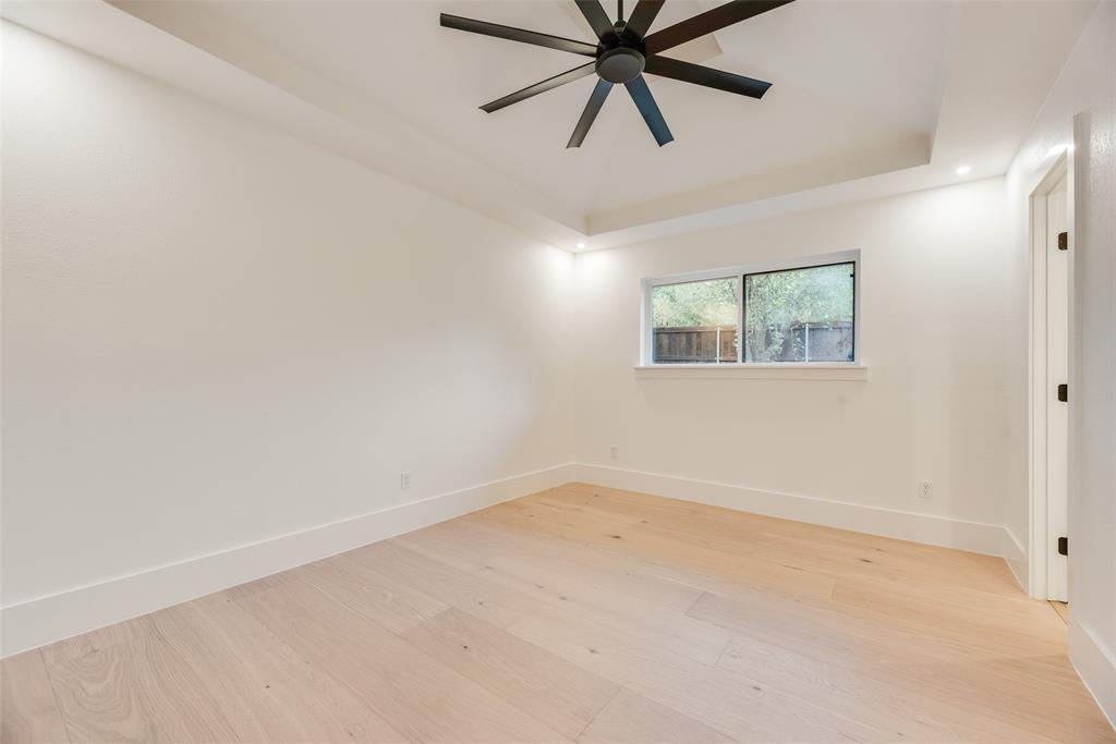 Tray ceiling featuring a matte black multi-blade ceiling fan, light-toned wood-finish flooring, and recessed lighting