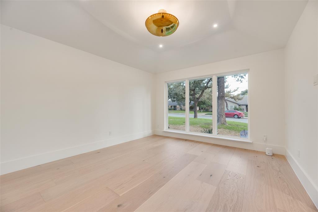 Interior space featuring light-toned wood-finish flooring, high tray ceiling, large picture window, and a modern gold-finish semi-flush mount light fixture